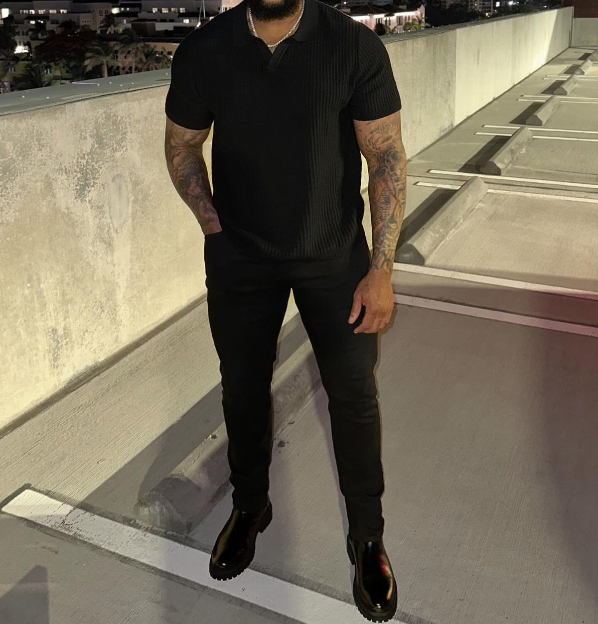 Man in all-black outfit wearing polished black leather loafers on a rooftop