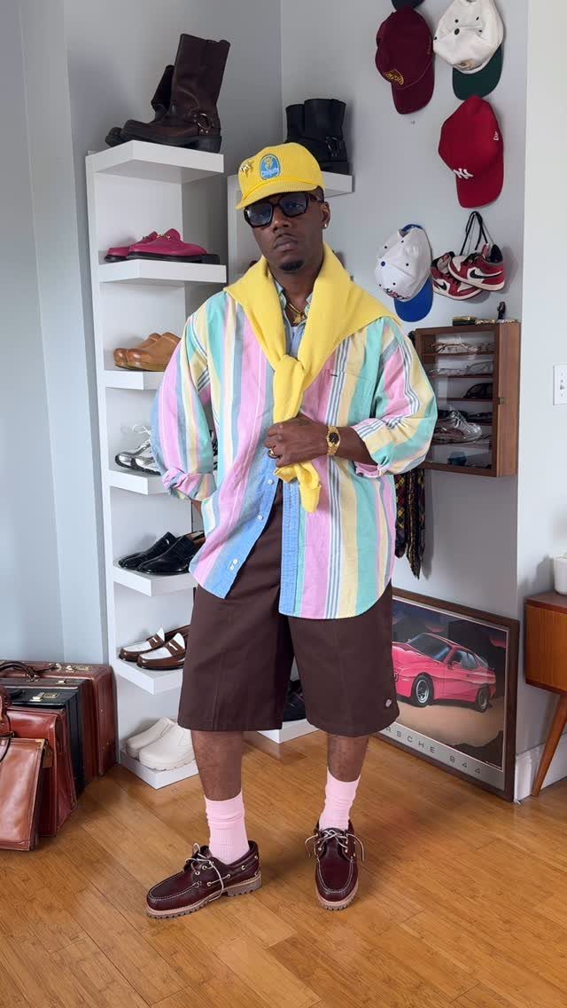 Man wearing brown boat shoes, pink socks, and brown shorts in a room.