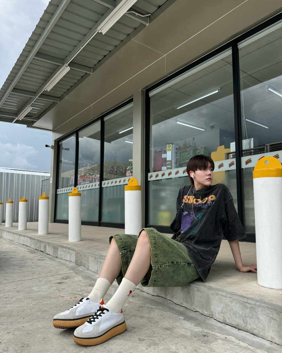 Person in oversized black tee and olive wide-leg trousers wearing white sneakers.