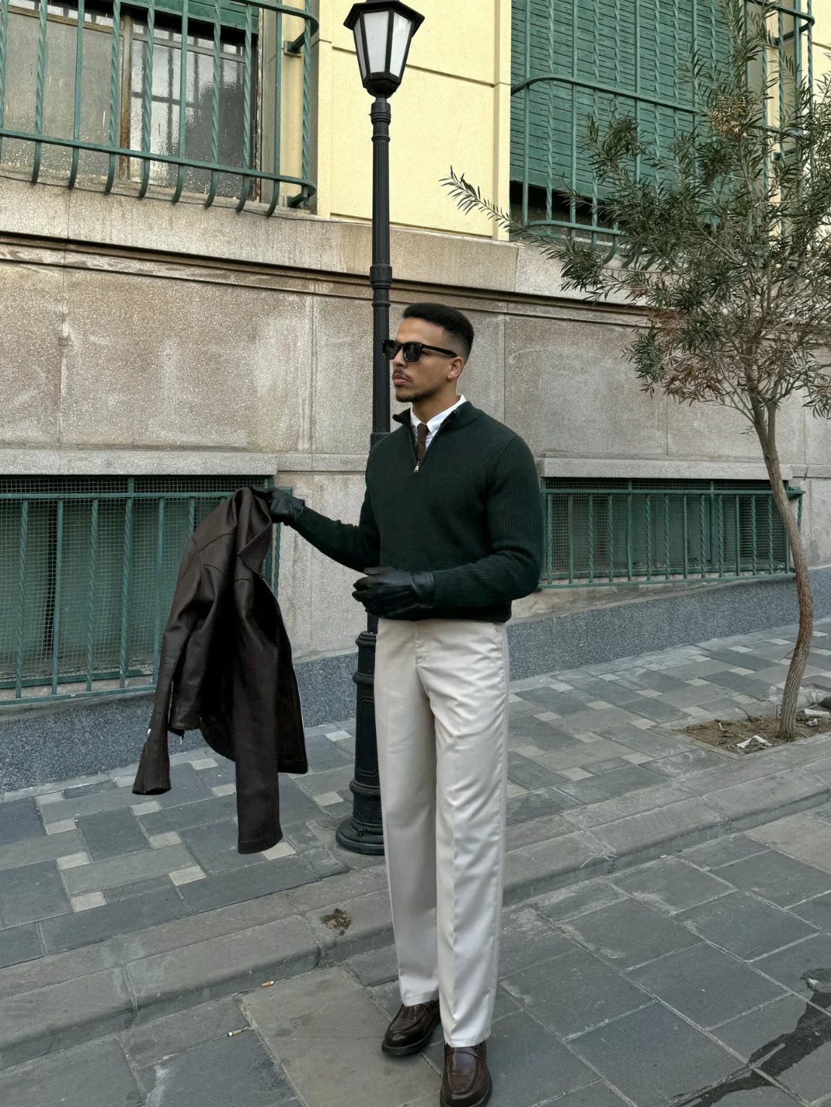 Man in green sweater and white chinos wearing brown leather dress boots.