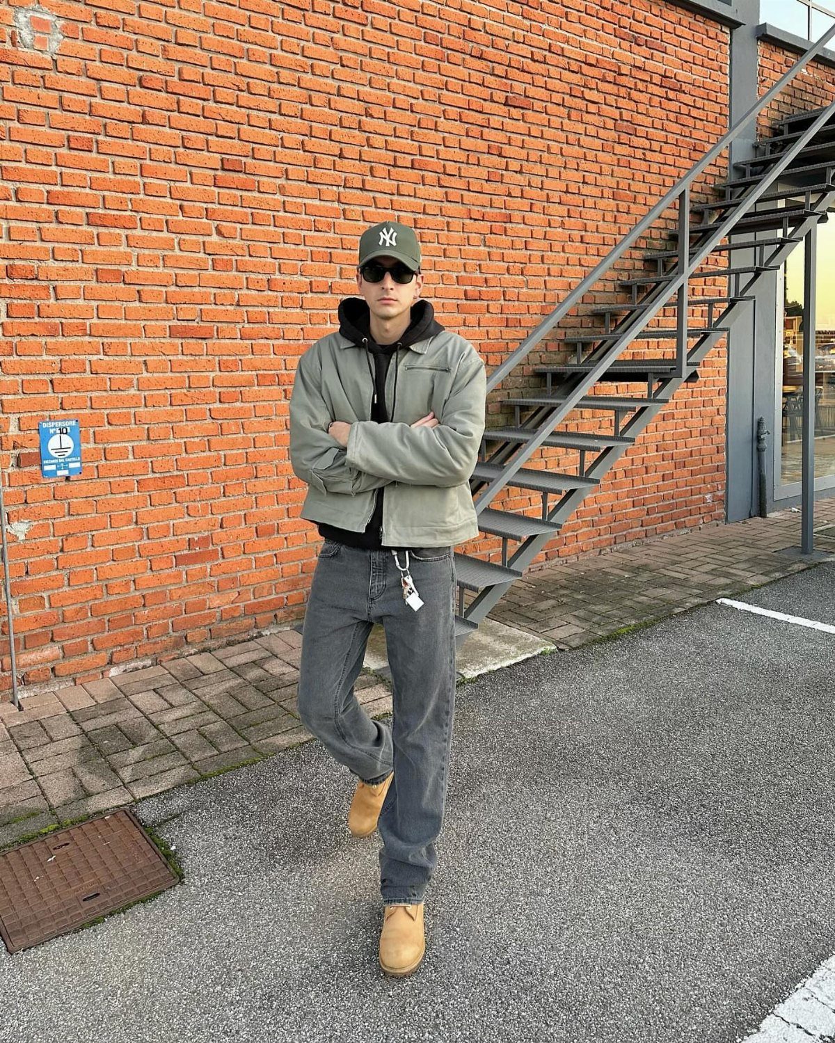 Man wearing tan work boots, grey jeans, and a light green jacket outdoors.