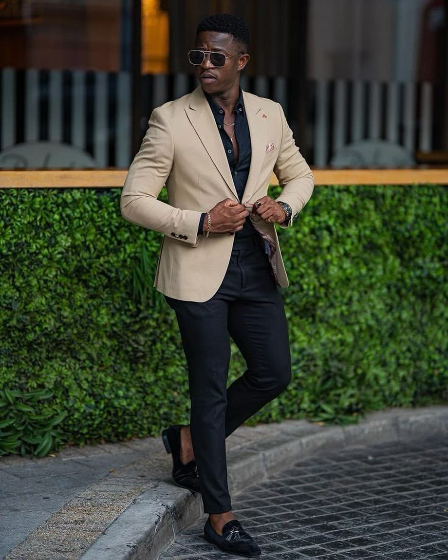 Man in beige blazer and black trousers wearing black leather slip-on loafers.