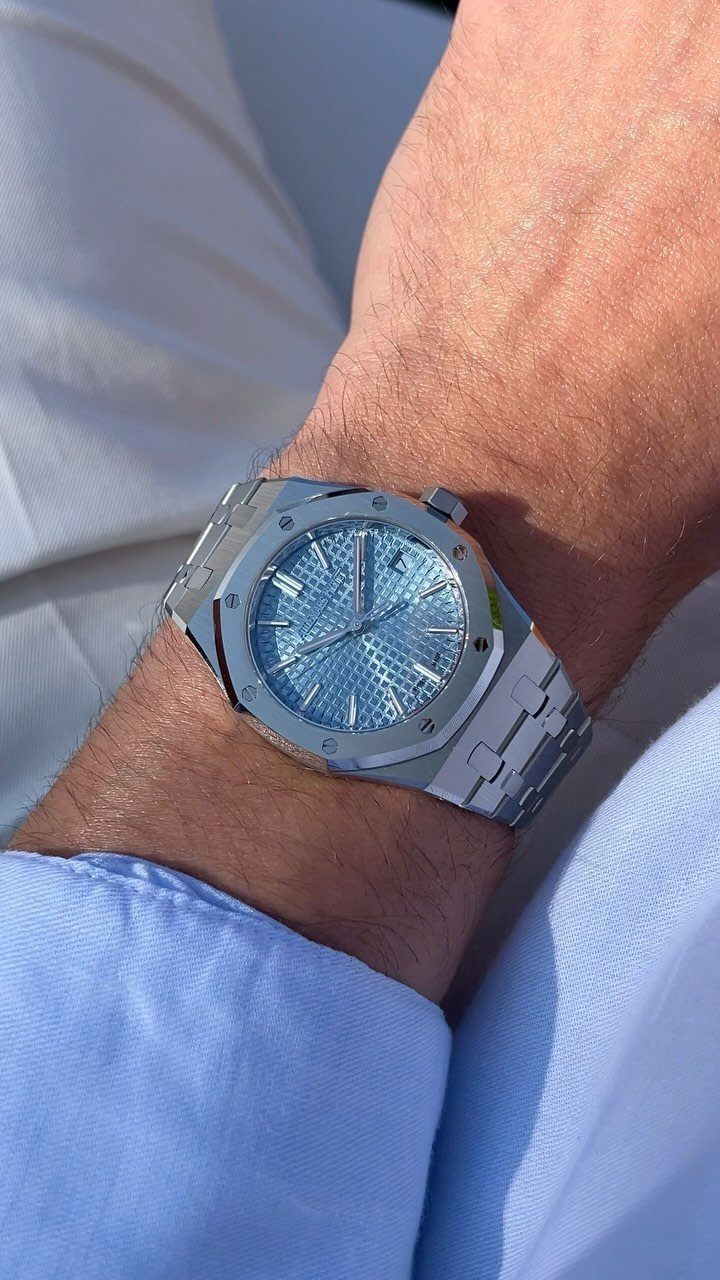 Silver luxury wrist watch with light blue dial on a man's wrist