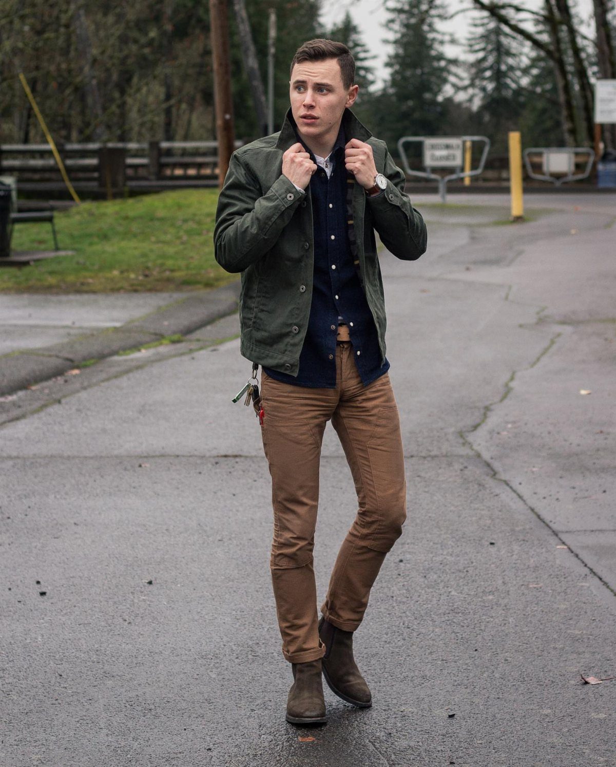 Man wearing a green jacket, navy shirt, brown pants, and brown leather boots.