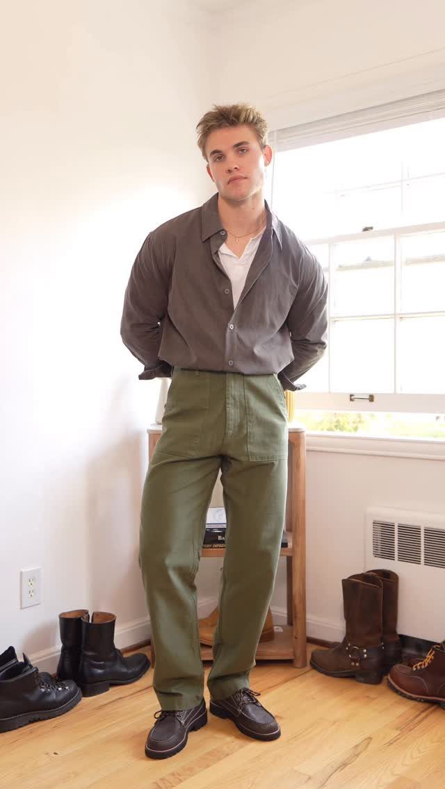 Man wearing a grey shirt, olive trousers, and brown leather Duke boots.
