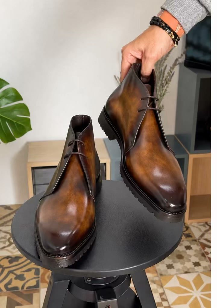 Brown leather chukka boots with thick soles displayed on a grey circular table.