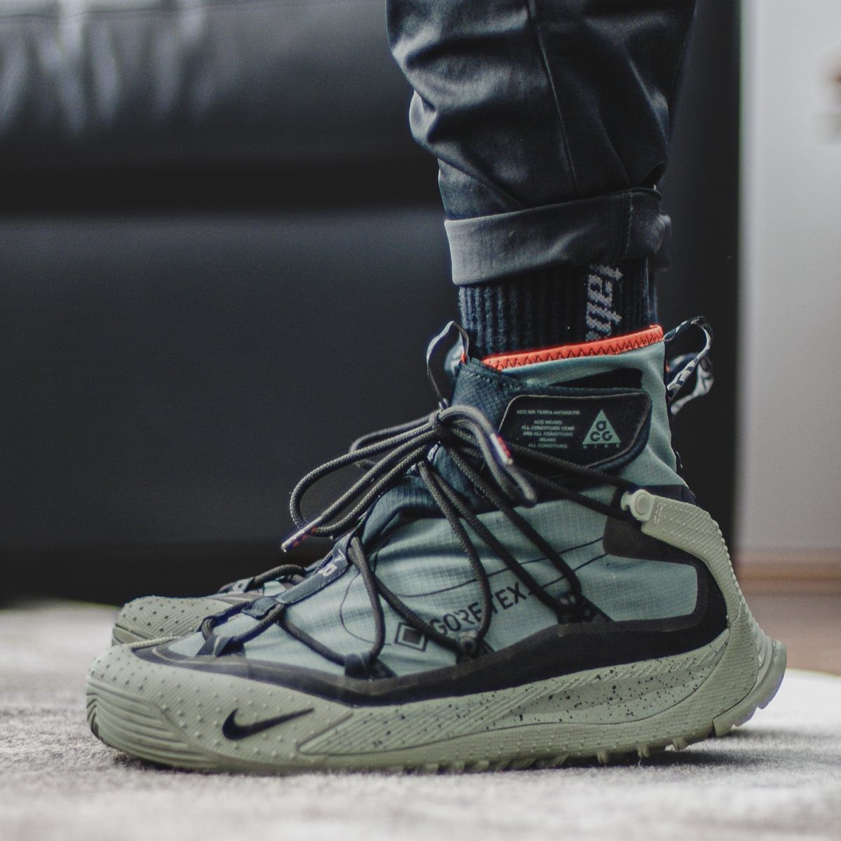 Olive green tech-utility boot with GORE-TEX fabric and thick textured sole on feet.