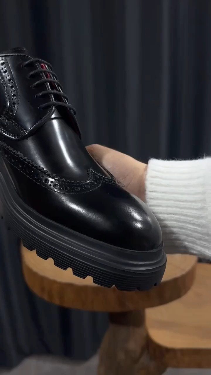 Black leather brogue shoe with decorative perforations and a thick lugged sole.