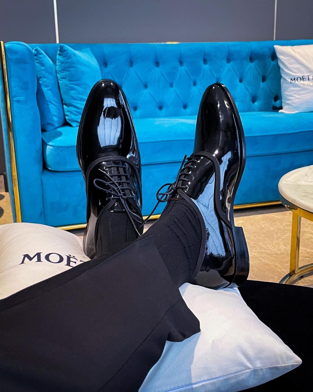 Black patent leather tuxedo dress shoes worn with black socks and trousers.