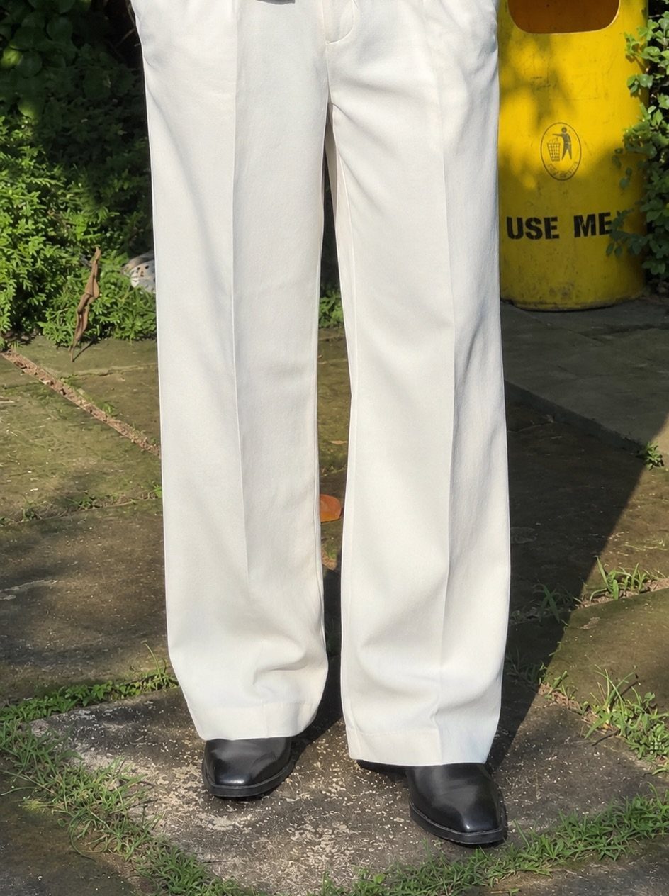 Wide-leg white trousers paired with polished black leather dress shoes on concrete.