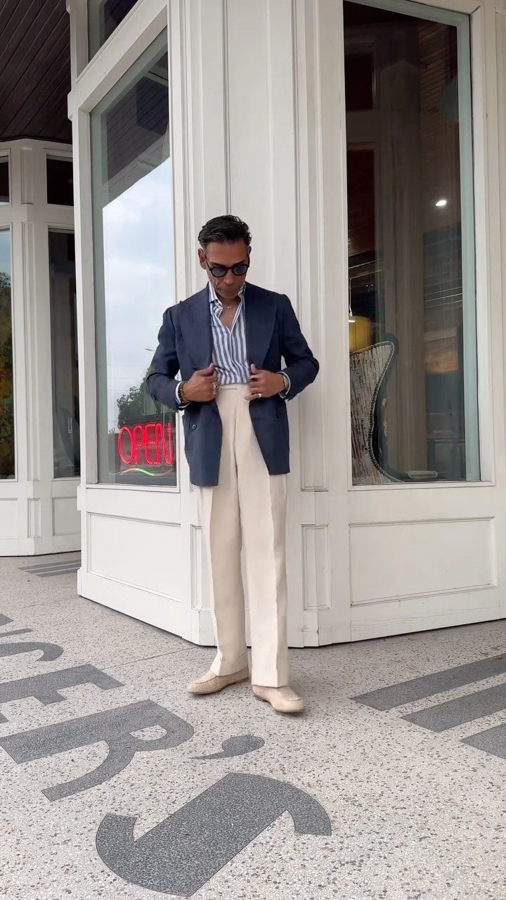 Man in navy blazer and white pants wearing tan suede loafers outdoors.