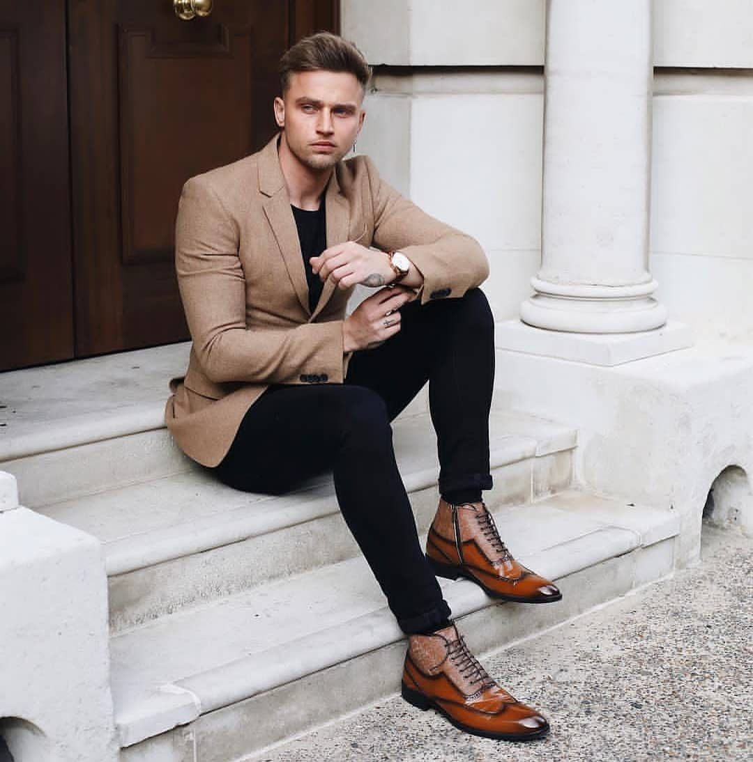 Man in tan blazer and black trousers wearing brown leather dress boots.