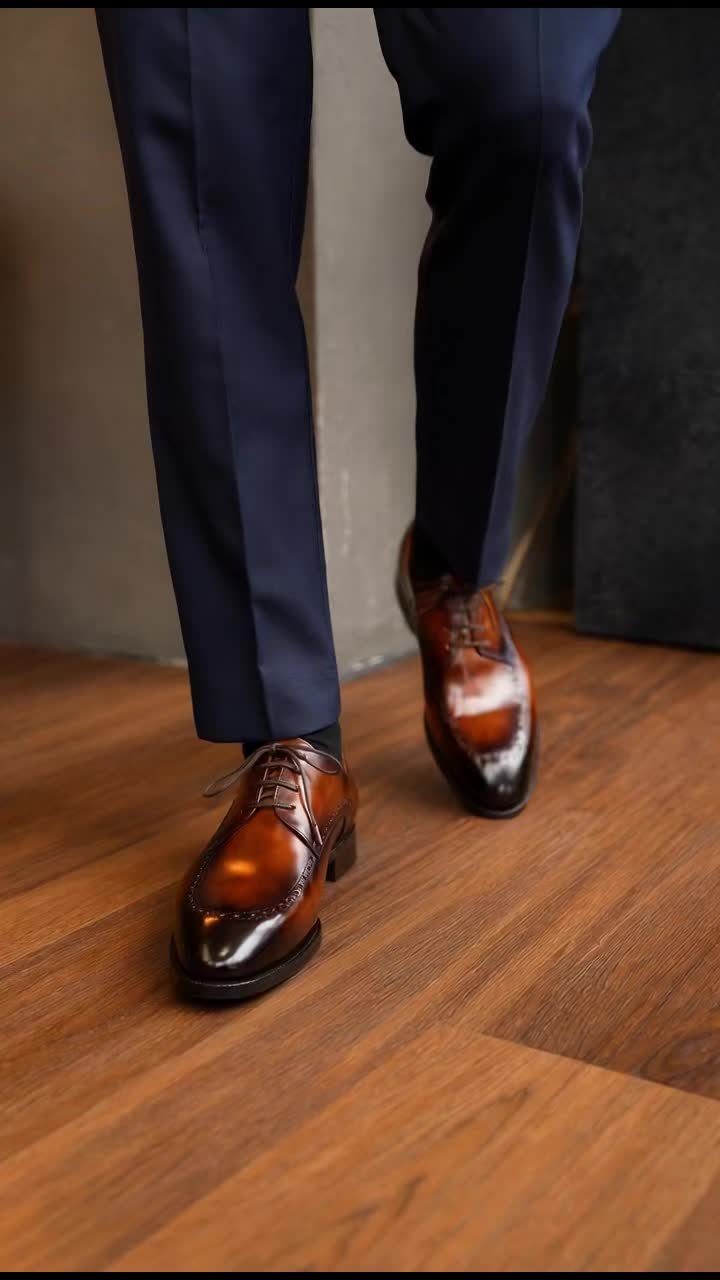 Navy blue dress trousers paired with polished tan leather oxford shoes on wood floor