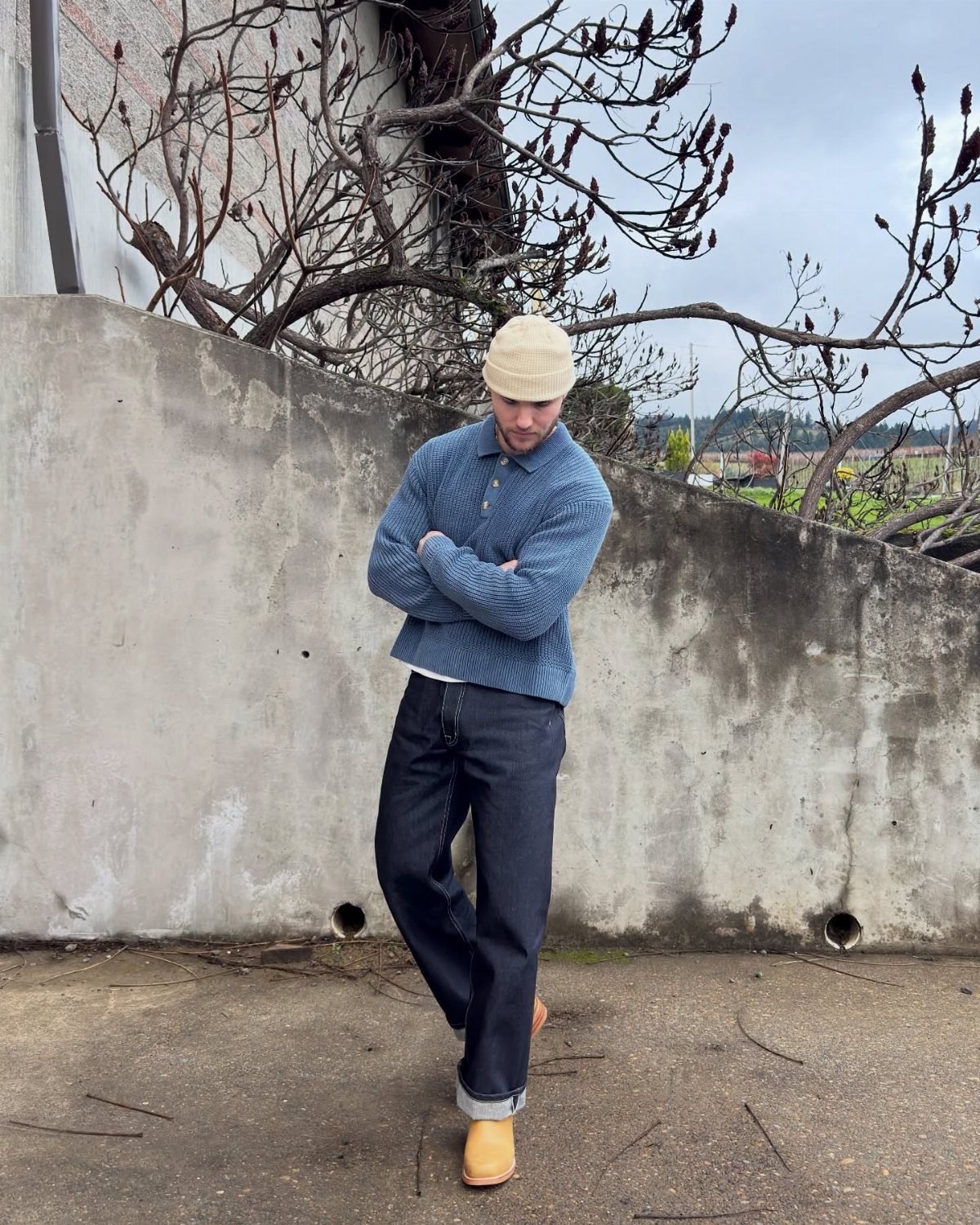 Man in blue sweater and dark jeans wearing tan winter boots