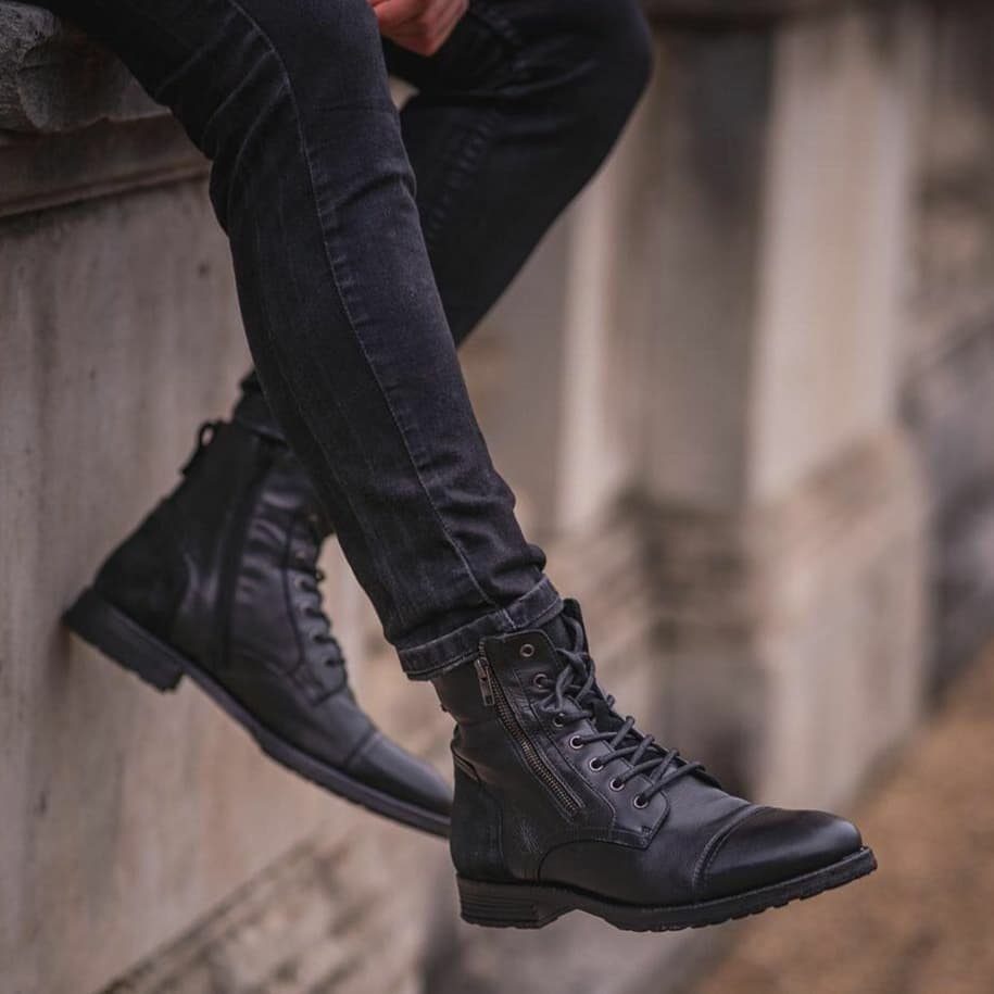 Black leather lace-up boots with side zippers worn with black slim-fit jeans.