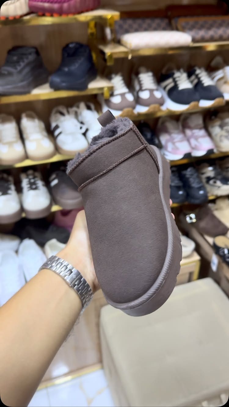 Brown suede ankle boot with fur lining held in front of shoe store shelves