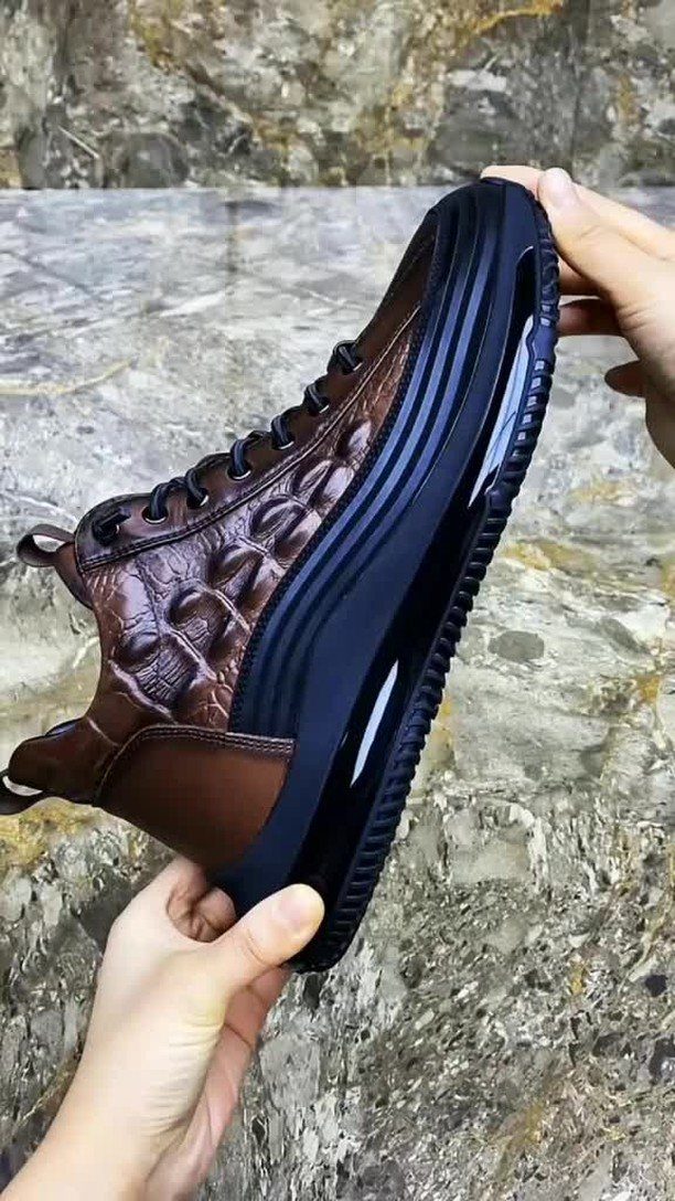 Brown leather high-top sneaker with a thick black platform sole held by hands.