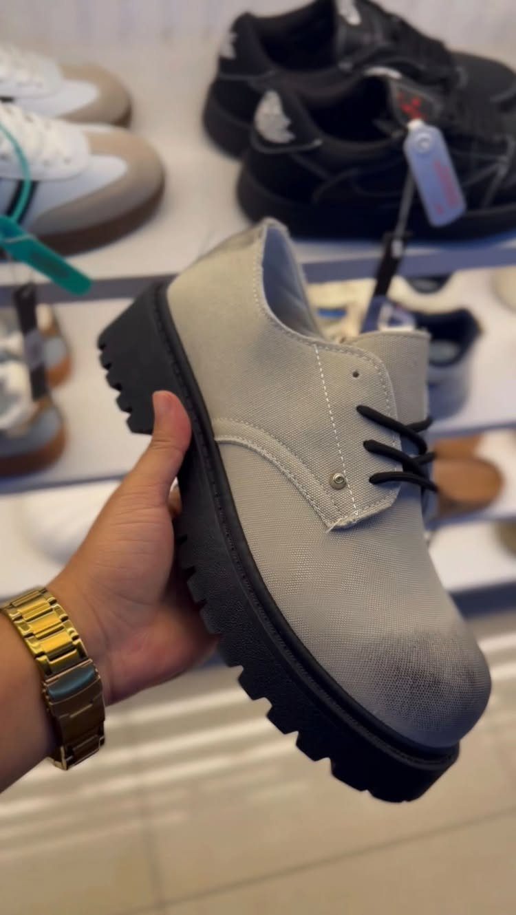 Light grey canvas boot with a thick black chunky lug sole held by hand.