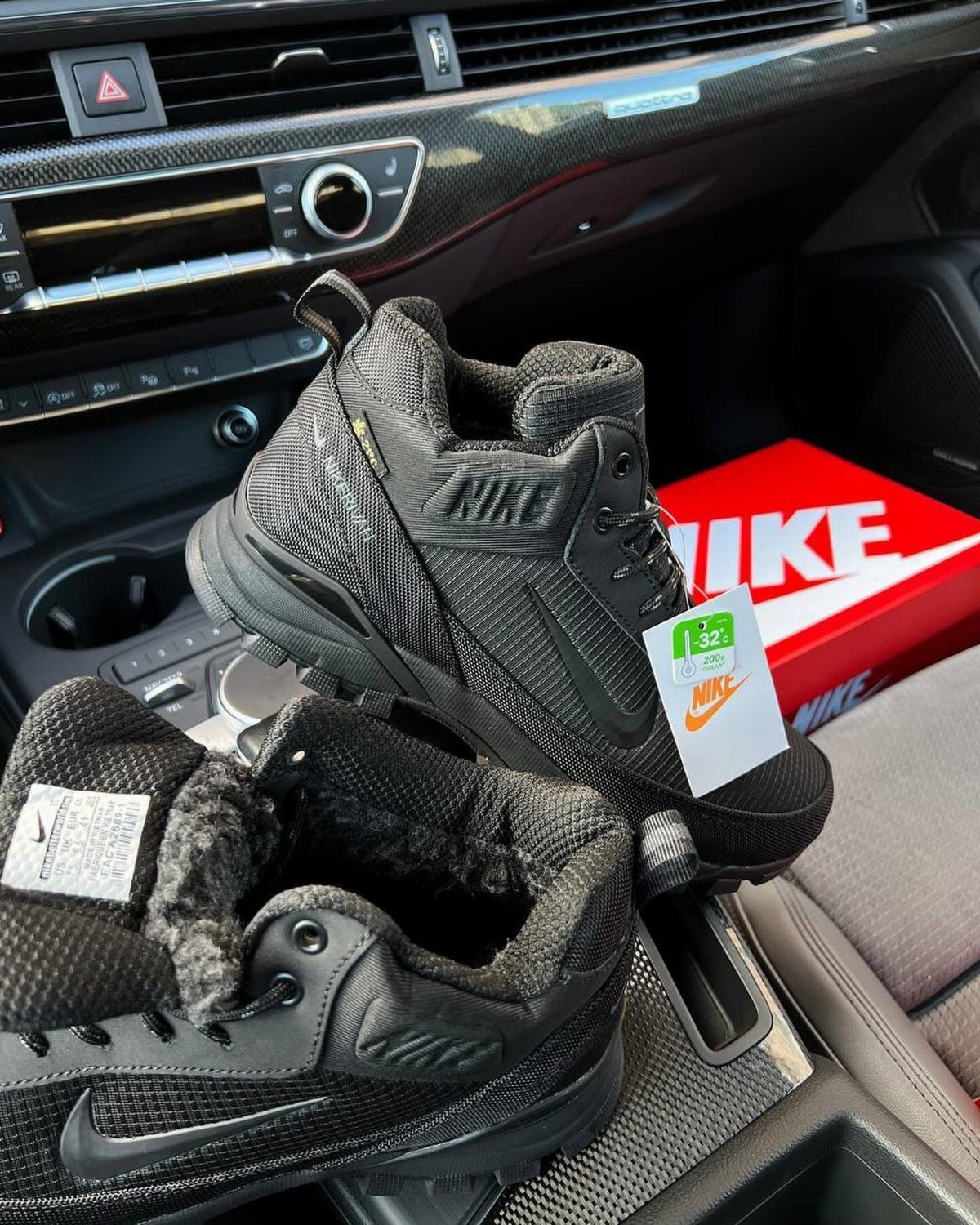 Black Nike winter boots with fur lining resting inside a car interior.